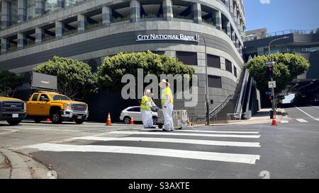 LOS ANGELES, CA, LUGLIO 2020: Due lavoratori che segnano un attraversamento pedonale con strisce bianche all'incrocio nel quartiere finanziario del centro Foto Stock