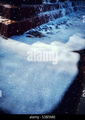 L'acqua, la neve e i gradini marroni della fontana Foto Stock