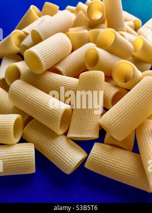 Paccheri maccheroni Pasta grezza secca italiana bronzo trafilato, pasta Gragnano, Napoli, Italia su sfondo blu vista dall'alto Foto Stock
