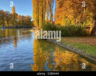 Stagno in Englischer Garten (Giardino Inglese) a Monaco con riflessi alberi d'autunno. Foto Stock