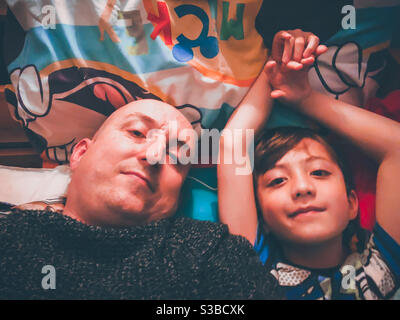 Padre e figlio selfie, sdraiati a letto al momento di coricarsi. Foto Stock