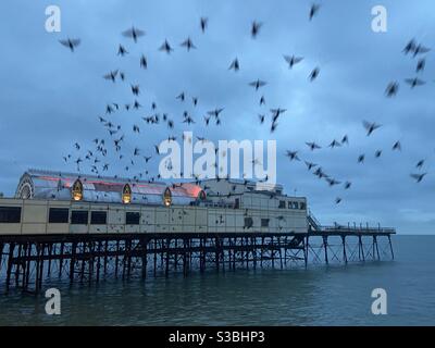 Aberystwyth, Galles occidentale, Regno Unito. Mercoledì 2 dicembre 2020. Meteo: Le stelle scoppiano da sotto il Royal Pier con un suggestivo paesaggio torbido alle loro spalle. Credito fotografico ©️ Rose Voon / Alamy Live News. Foto Stock