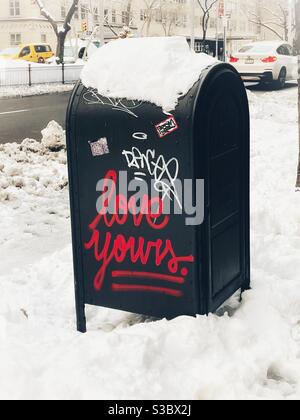 Graffiti rossi su una cassetta postale innevata su Park Avenue in New York City durante una tempesta invernale Foto Stock
