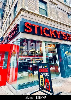 Segnaletica rossa e blu dai colori vivaci su un bar della zona, Sticky's Finger joint serve pollo fritto e altri piatti da cucina casalinga a Murray Hill, New York City, USA. Foto Stock