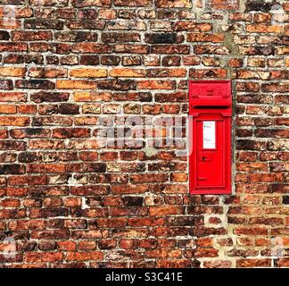 Una scatola postale Royal Mail rossa montata a parete o una scatola di lettere all'interno una parete di mattone con spazio di copia Foto Stock