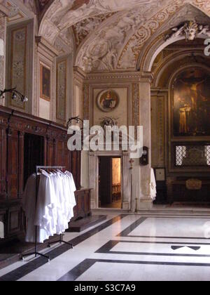 Paramenti di sacerdoti cattolici appesi in treno in una splendida e opulenta sala della cattedrale di Roma Italia. Foto Stock