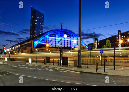 Lunga esposizione di un tram nel centro di Manchester City con edifici iconici sullo sfondo. Foto Stock