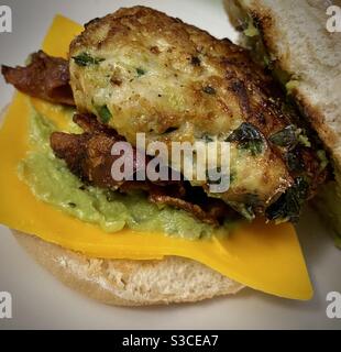 Hamburger di spinaci con avocado di pollo fatto in casa con formaggio e pancetta su pane artigianale tostato. Foto Stock