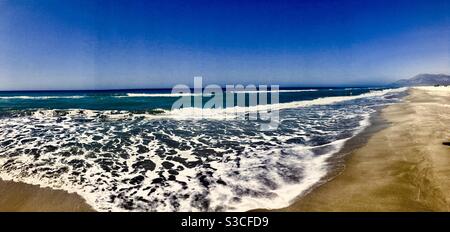 Ampio angolo di navigazione e dolci onde con schiuma lungo la spiaggia di sabbia poco profonda sulla costa meridionale della Turchia, nel luminoso sole estivo. Patara Beach, Turchia. Foto Stock