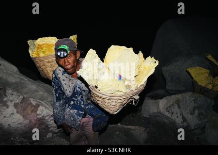 Operaio che effettua zolfo fuori del cratere del monte Ijen in Oriente Java Indonesia Foto Stock