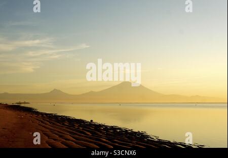 Monte Agung con vista sul mare dalla spiaggia di Sanur a. alba Bali Indonesia Foto Stock