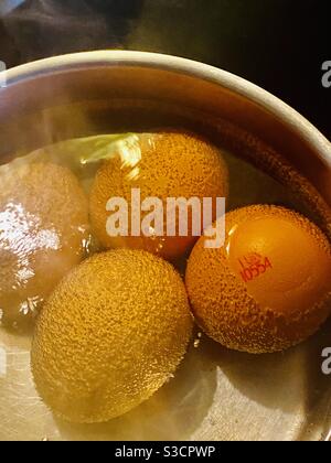 Uova bollite in acqua bollente in una padella di alluminio Foto Stock