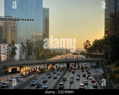 LOS ANGELES, CA, NOVEMBRE 2020: Guardando a sud il traffico retroilluminato sulla superstrada CA-110 che passa da uffici, hotel e appartamenti del centro al tramonto Foto Stock