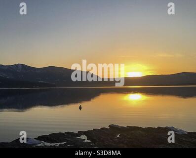 Guardando il sole scendete dalla spiaggia mentre la giornata finisce e si trasforma in notte. Tutto rallenta e diventa pacifico. Foto Stock