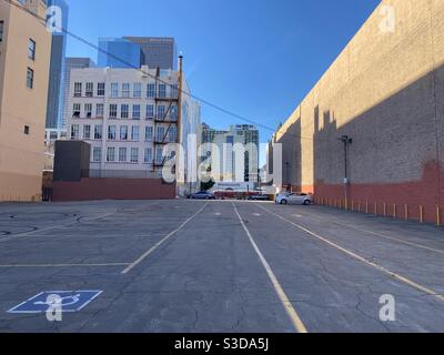 LOS ANGELES, CA, NOVEMBRE 2020: Parcheggio per lo più vuoto in centro con autobus ROSSO LA Metro che passa di fronte a una cappella ispanica di nozze all'estremità, grattacieli visibili sopra edifici vicini Foto Stock