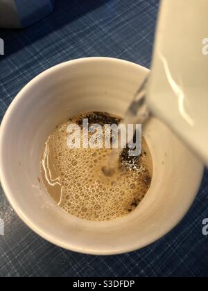 Versare acqua bollente per preparare un caffè istantaneo Foto Stock