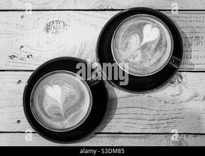 Due tazze di caffè con latte art a forma di cuore piano di legno Foto Stock