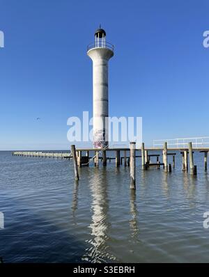 Vecchio faro di Broadwater Marina con molo e riflessi sulla Golfo del Messico acqua Foto Stock