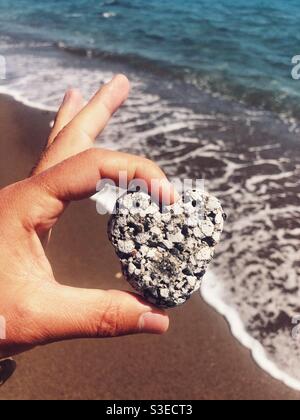 Roccia a forma di cuore tenuta in mano dal mare Foto Stock