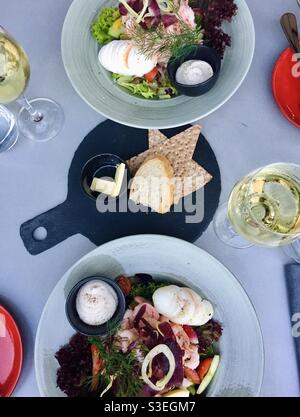 Tavolo con insalata di gamberi e due bicchieri di vino bianco e pane per due persone da sopra. Foto Stock