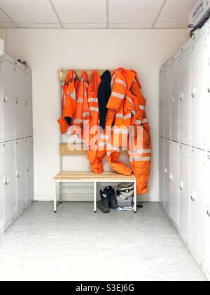 Un armadietto nel settore edile o ferroviario con DPI ad alta visibilità o indumenti da lavoro appesi ai ganci Foto Stock