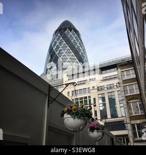 Un assaggio della cima del grattacielo Gherkin nella Città di Londra. In primo piano ci sono cesti appesi fatti di caschi da cantiere Foto Stock