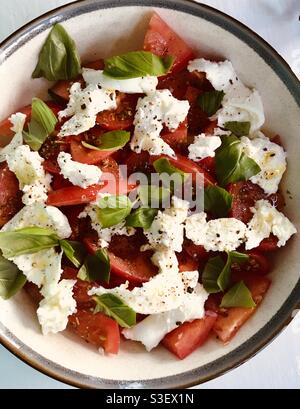 Ciotola di insalata caprese italiana con pomodori mozzarella al basilico foglie e olio d'oliva Foto Stock