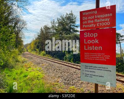 Avviso di avvertimento accanto a una linea ferroviaria a binario unico attraverso la campagna Foto Stock