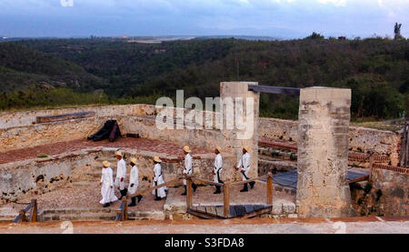 I giovani cadetti in uniforme entrano a Castillo de San Pedro de la Roca o al Castello Morro al crepuscolo per la mostra di sparo a pistola per i turisti, Santiago de Cuba, Cuba Foto Stock