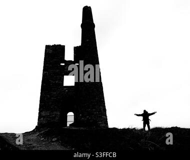 Cornovaglia in Silhouette - uomo in piedi accanto ad una vecchia rovina di una miniera di Cornovaglia. Bianco e nero. Foto Stock