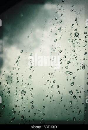 Gocce di pioggia sul vetro con cielo nuvoloso. Immagine a tema meteo con spazio per le parole Foto Stock