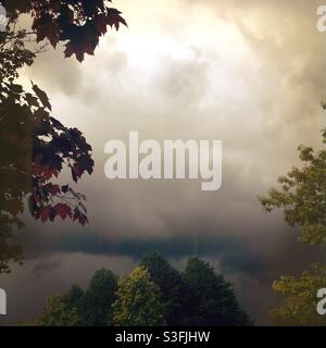 Cielo nuvoloso delimitato da alberi intorno alla maggior parte dell'immagine. Colori neutri in oro marrone seppia con delicato effetto moody. Spazio di copia vuoto sull'espansione delle nuvole Foto Stock