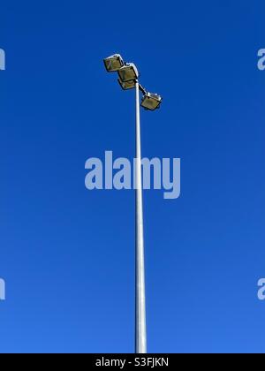 Torre faro su un terreno sportivo contro il cielo blu Foto Stock