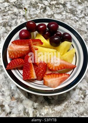 Fragole, ananas e ciliegie in un recipiente. Foto Stock