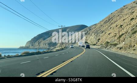 MALIBU, CA, DEC 2020: Vista verso nord mentre si guida sulla Pacific Coast Highway 1 con le montagne davanti e l'Oceano Pacifico sulla sinistra Foto Stock