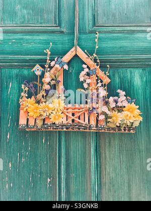 Incantevole decorazione estiva primaverile su una porta verde in difficoltà. Stile vintage. Foto Stock