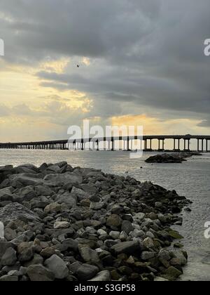 Cielo tempestoso e dorato al tramonto su Destin, il ponte della Florida e il Golfo del Messico Foto Stock