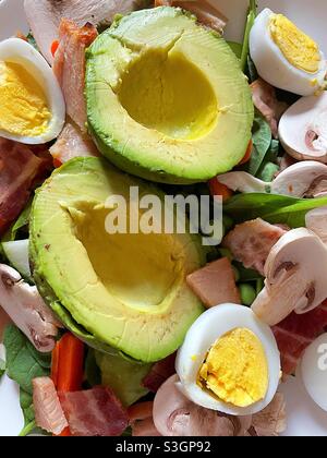 Primo piano di un'insalata appena tostata con mezzi di avocado, funghi e un po' di lattuga tritata Foto Stock