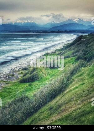 La costa più meridionale dell'isola meridionale della Nuova Zelanda con le Alpi meridionali sullo sfondo Foto Stock