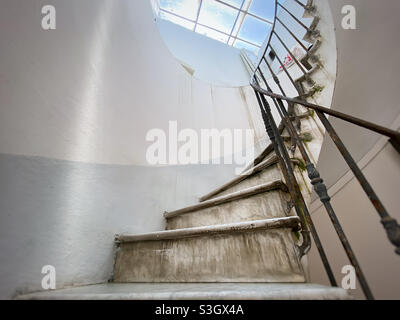 Antica scala a chiocciola con scalini in marmo e corrimano in ferro battuto. Luce naturale proveniente dal lucernario. Architettura e forma circolare Foto Stock