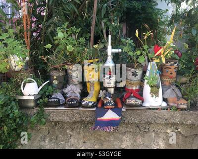 Amasra Türkiye’de bir evin arka bahçesinde eski ayakkabı ve çizmelere ekilmiş bitchiler, piante piantate in vecchie scarpe e stivali nel cortile di una casa ad Amasra, Turchia Foto Stock