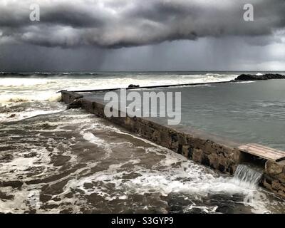 Cielo di Moody e grandi nuvole tempeste sull'Oceano Indiano e sulla piscina di Thompson's Bay a Ballito, in Sud Africa Foto Stock