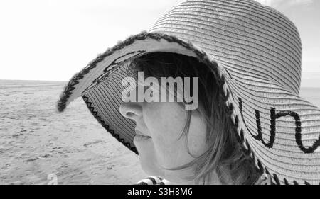 Donna in cappello da spiaggia sulla spiaggia in profilo bianco e nero Foto Stock