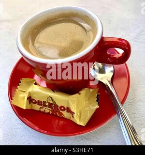 Tazza di caffè fresco con un degustatore Toblerone in miniatura gratuito. Foto Stock