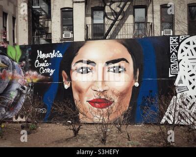 Un murale del Congresso degli Stati Uniti Alexandria Ocasio-Cortez a Manhattan, New York. I cespugli di primo piano danno l'aspetto dei capelli del viso. Foto Stock