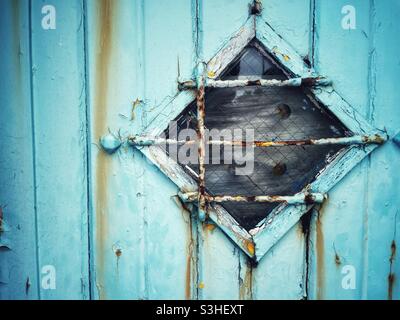 Vecchia porta intemperie con finestra diamantata. Foto Stock