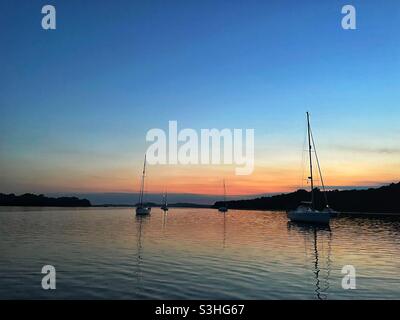 Crepuscolo e calmo serale ad un ancoraggio a Poole Harbour sulla costa meridionale dell'Inghilterra Foto Stock