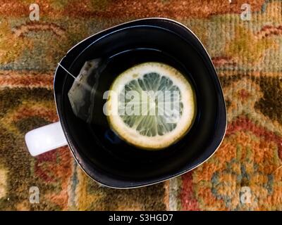 Tè verde con fetta di limone fresco, una bevanda salutare, seduto su un tappeto orientale, Canada. Spesso combinato con miele, zenzero ed erbe. Infusione stimolante. Asiatico. Foto Stock