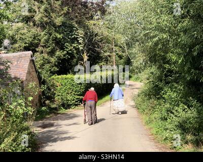 Una coppia anziana cammina lungo una corsia di campagna in Oxfordshire, Regno Unito Foto Stock