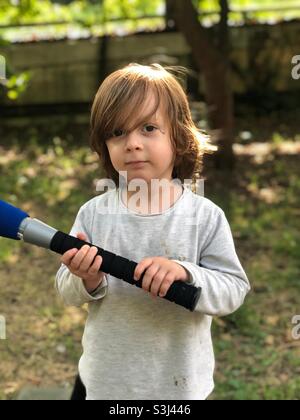 Bambino di quattro anni all'aperto con una spada laser. Foto Stock